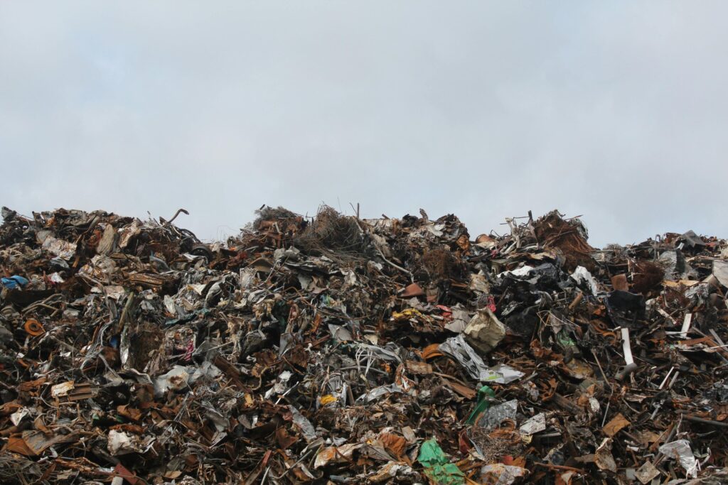 pexels-photo-128421-128421 A large pile of scrap metal and waste at a landfill against a cloudy sky.
